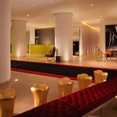 Hotel St Martins Lane Londýn Exteriér fotografie The photo shows a modern and stylish interior space, possibly a lobby or a lounge area. It features sleek white pillars and a polished floor, illuminated by soft ambient lighting. On one side, there is a green seating area, while on the opposite side