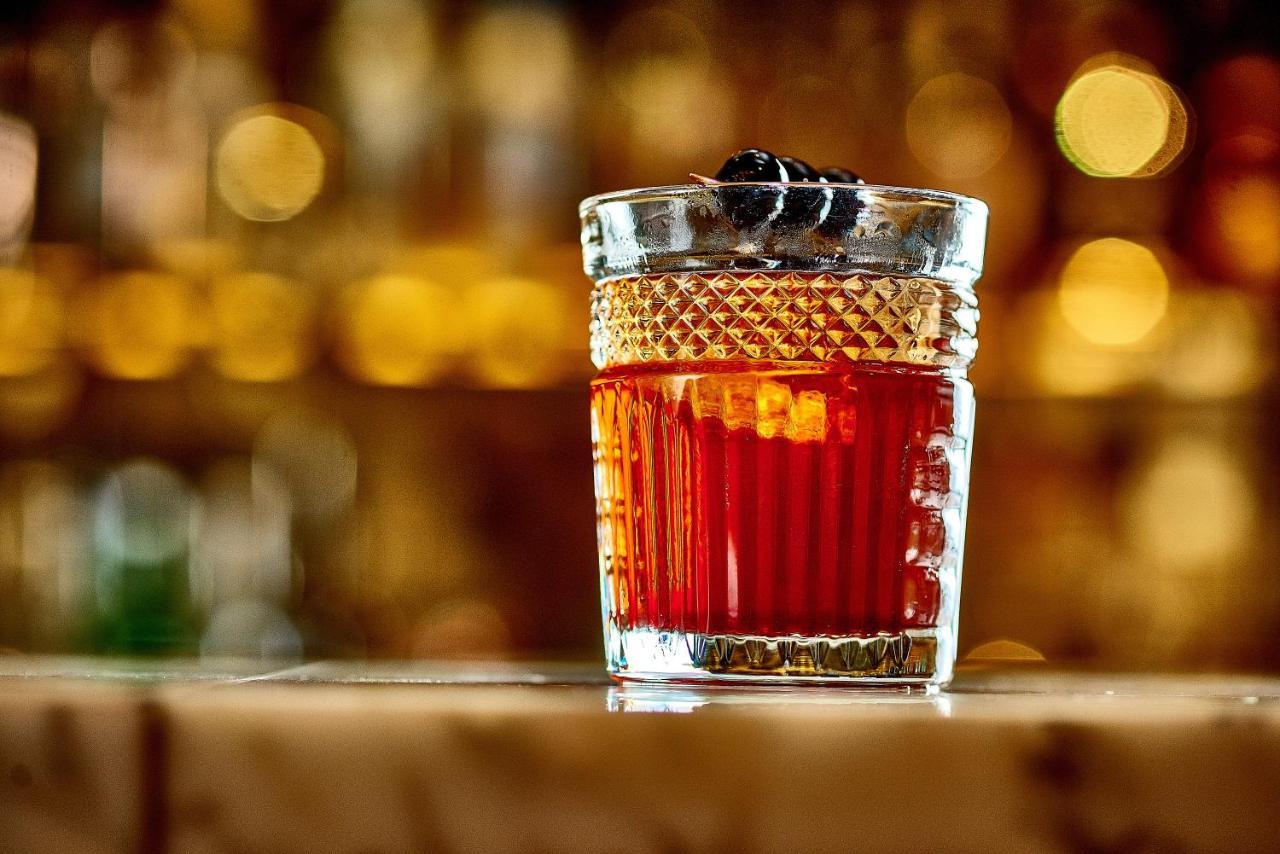 Hotel St Martins Lane Londýn Exteriér fotografie The photo shows a stylish glass filled with a dark red cocktail. The glass has a textured design and is topped with a couple of dark garnishes, possibly cherries. The background is softly blurred, highlighting the drink and suggesting a warm, invitin