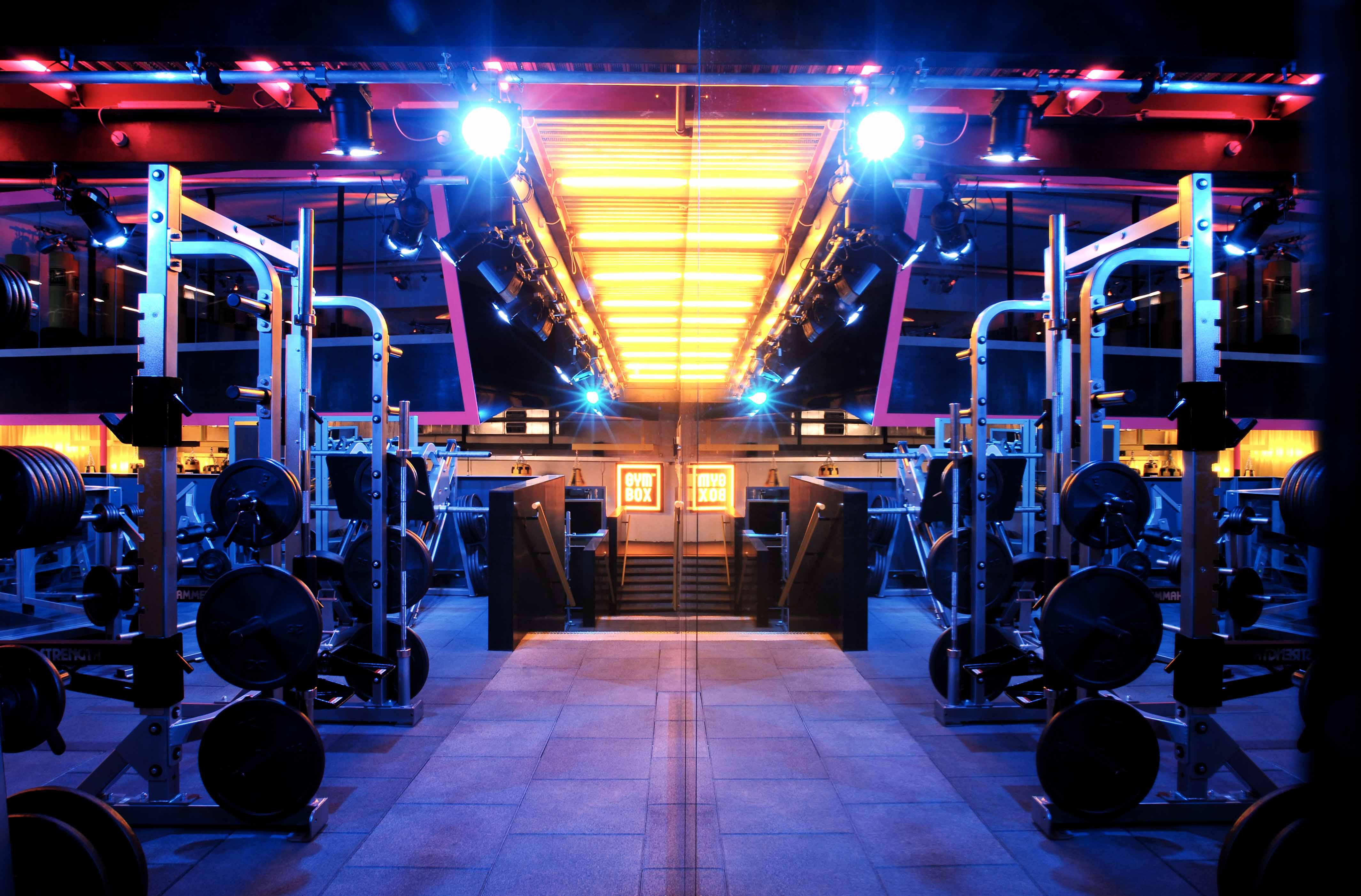 Hotel St Martins Lane Londýn Exteriér fotografie The photo depicts a modern gym interior, characterized by a brightly lit space with blue and orange lighting. In the foreground, there are multiple gym equipment setups, including weightlifting machines and benches. The gym features a sleek and conte