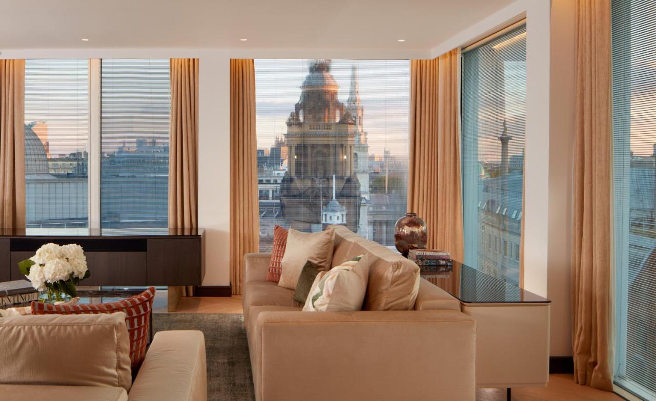 Hotel St Martins Lane Londýn Exteriér fotografie The photo depicts a stylish and modern living room space. The room features large windows with sheer curtains, allowing natural light to fill the area. A plush beige sofa with decorative cushions is positioned centrally, creating a cozy atmosphere. I