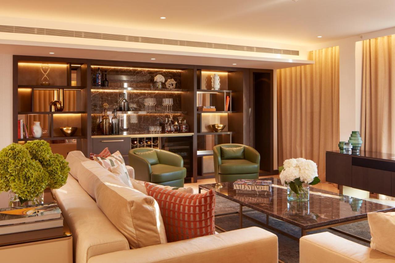 Hotel St Martins Lane Londýn Exteriér fotografie The photo depicts a modern and elegantly designed living room. It features a light-colored sofa with decorative cushions, positioning it as a central seating area. Two green armchairs are placed beside a glass coffee table, which sits atop a textured