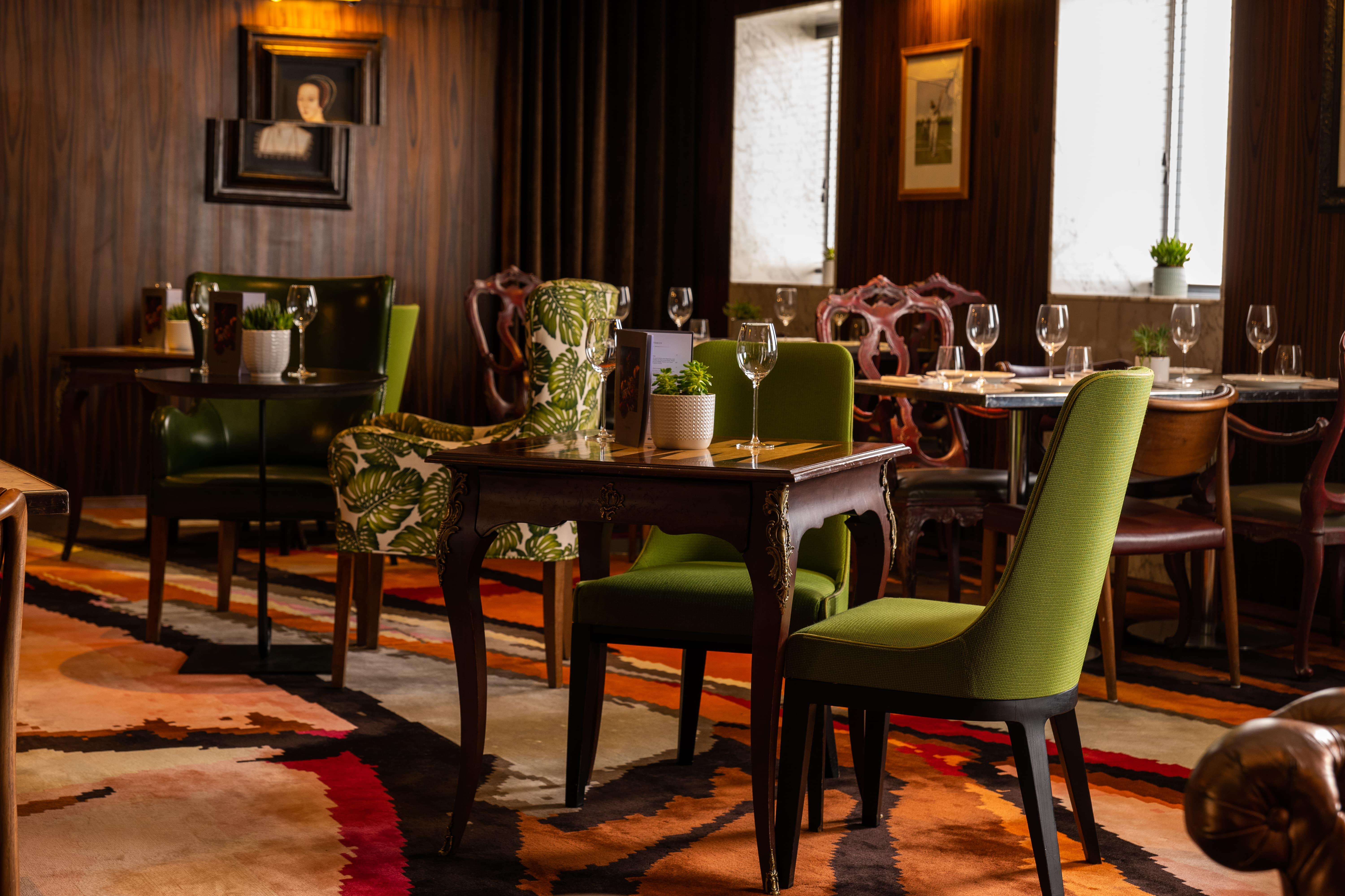 Hotel St Martins Lane Londýn Exteriér fotografie The image depicts an elegant dining area with a blend of classic and contemporary design elements. There are several tables arranged neatly, each accompanied by stylish chairs. Some chairs have vibrant green upholstery and unique patterns, while othe