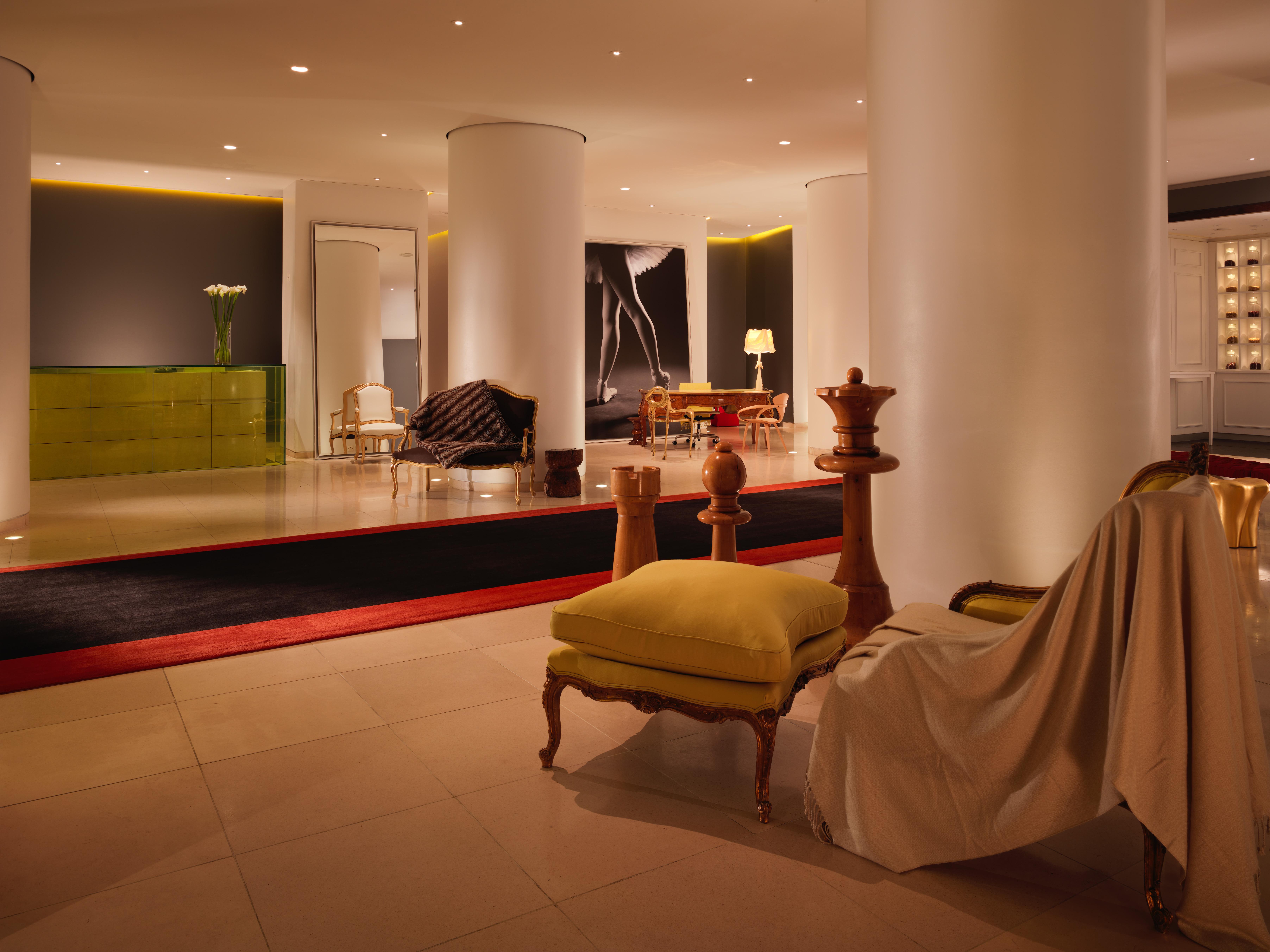 Hotel St Martins Lane Londýn Exteriér fotografie The photo shows a modern, stylish hotel lobby. It features a spacious open area with sleek white columns and subtle lighting. There are various seating arrangements, including a sofa and armchairs, with a mix of contemporary and classic design elemen
