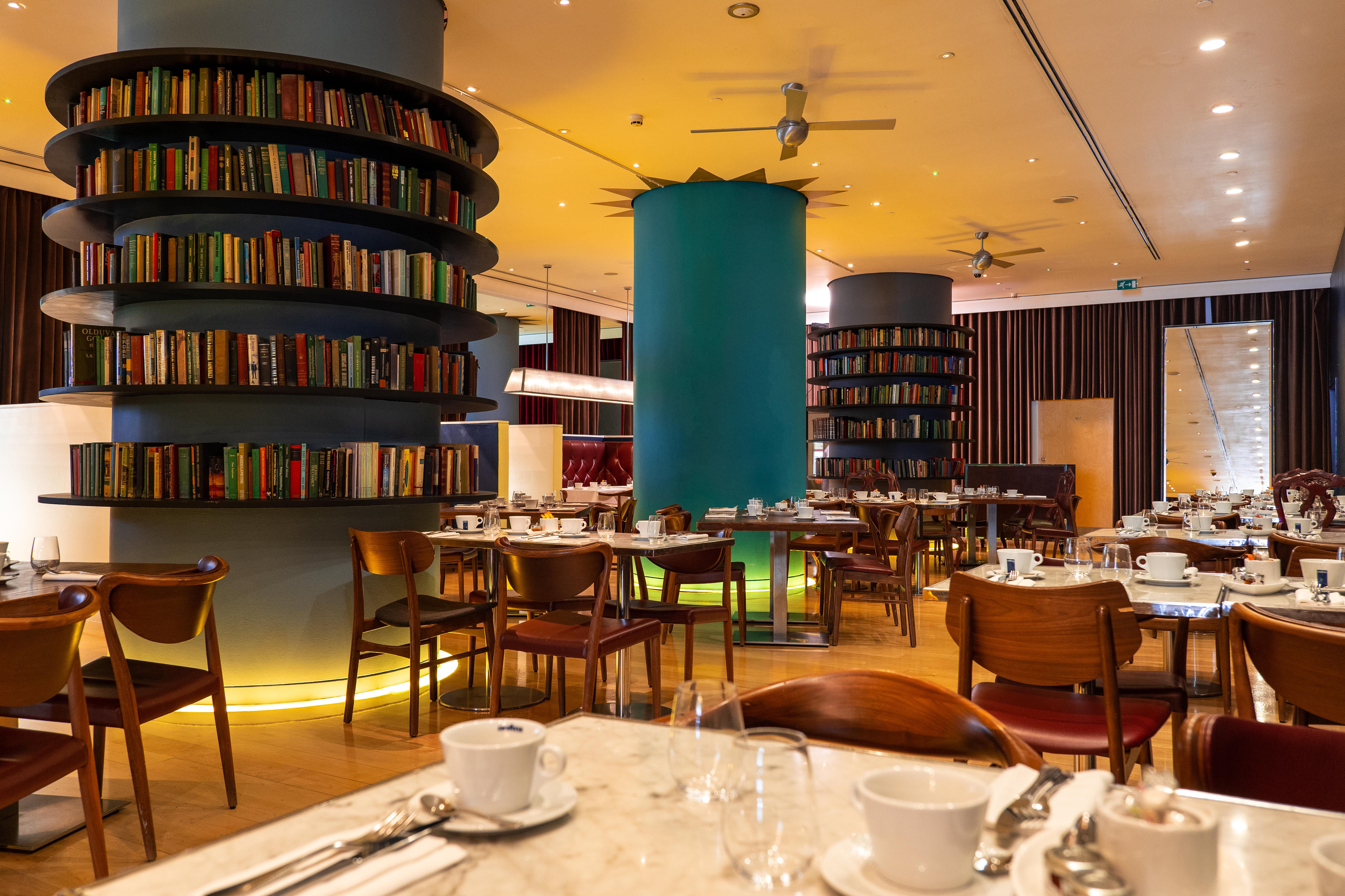 Hotel St Martins Lane Londýn Exteriér fotografie The photo depicts a modern restaurant interior featuring a warm and inviting design. There are round tables set for dining, each equipped with white tableware and cutlery. The restaurant has wooden chairs and is illuminated with soft lighting. 

Nota