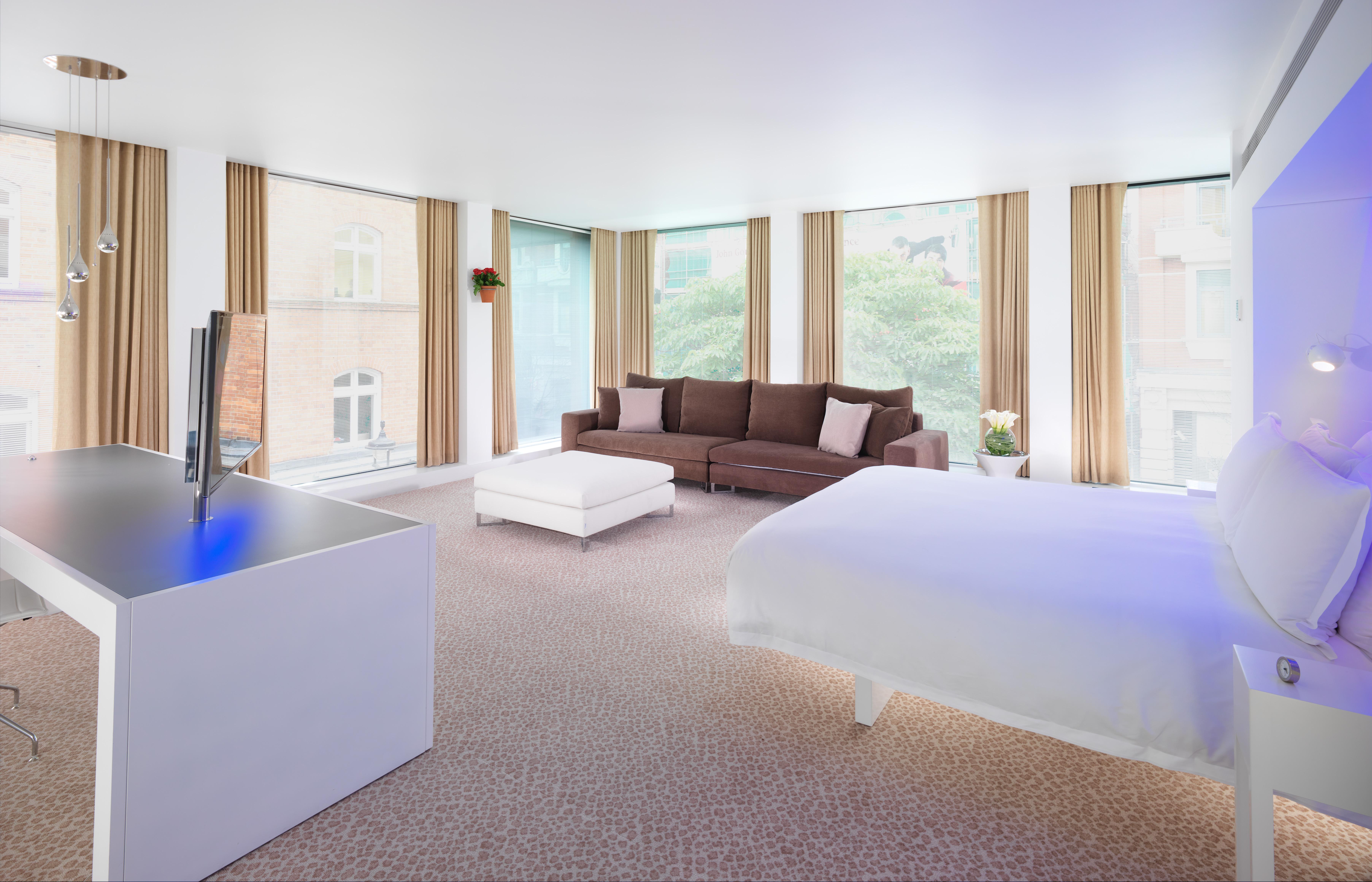 Hotel St Martins Lane Londýn Exteriér fotografie The photo shows a modern hotel room with a spacious and bright interior. On one side, there is a large bed with a white comforter. To the other side, there is a cozy brown sofa with some decorative cushions. A white coffee table is placed in front of