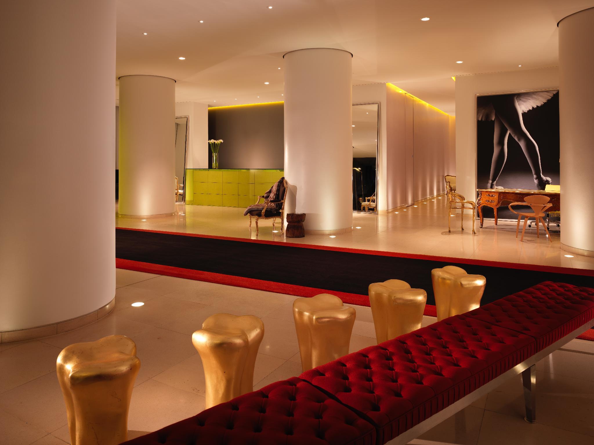 Hotel St Martins Lane Londýn Exteriér fotografie The photo shows a modern and stylish interior space, possibly a lobby or a lounge area. It features sleek white pillars and a polished floor, illuminated by soft ambient lighting. On one side, there is a green seating area, while on the opposite side