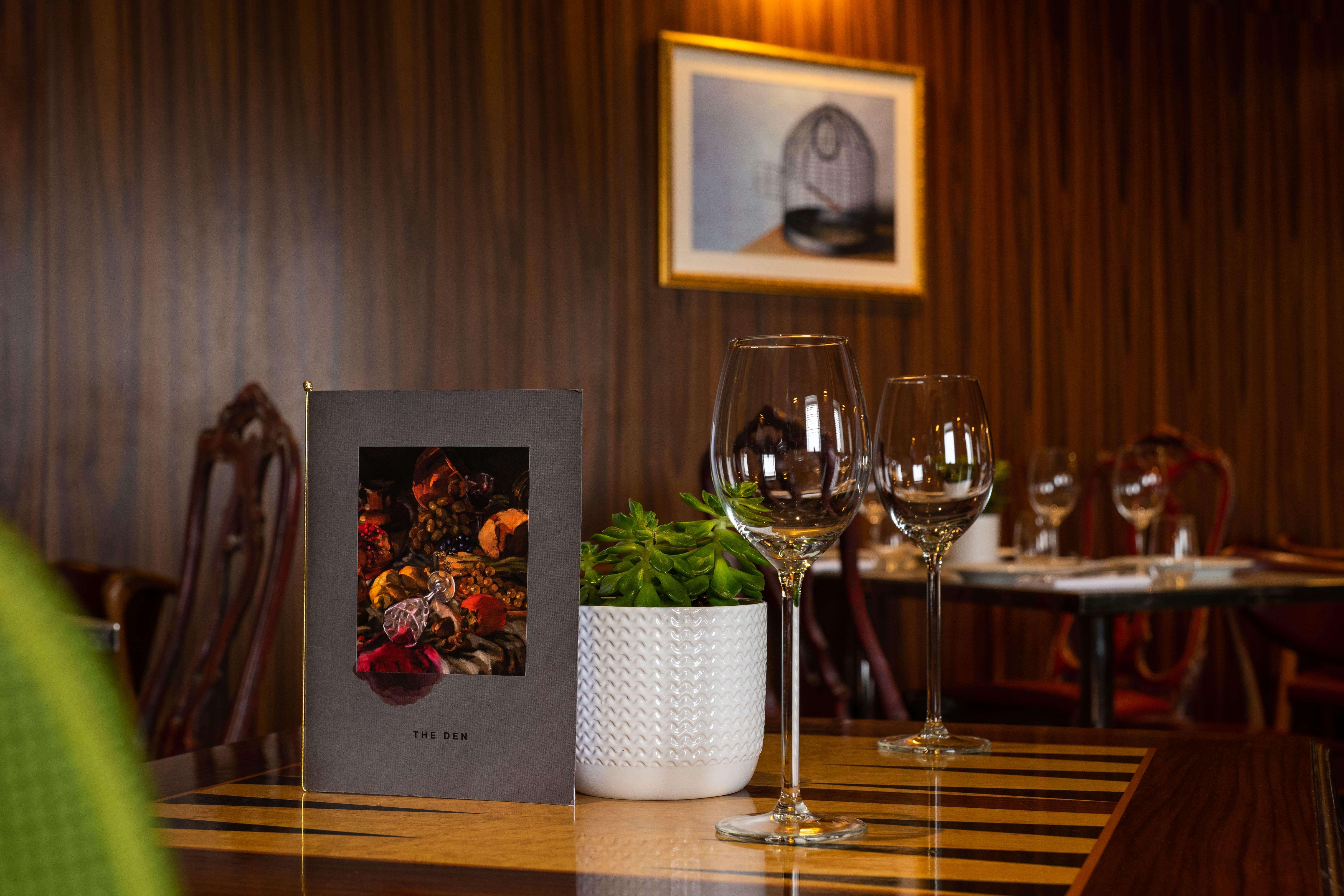 Hotel St Martins Lane Londýn Exteriér fotografie The photo shows a cozy dining setting in a restaurant. A menu is prominently displayed on the table, featuring a colorful design that includes images of spices or garnishes. Next to the menu, there are two elegant wine glasses, reflecting the ambianc