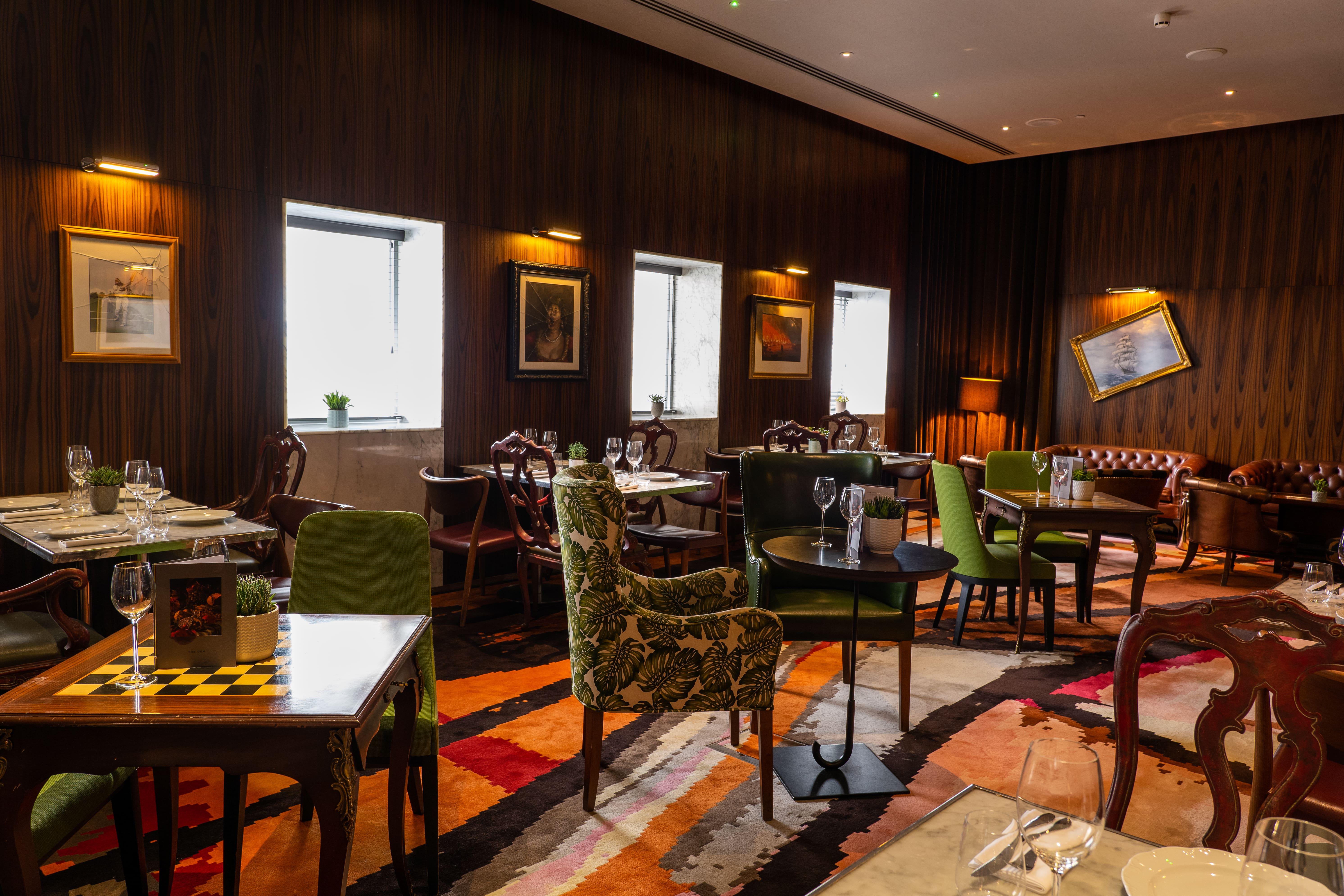 Hotel St Martins Lane Londýn Exteriér fotografie The photo depicts an elegantly designed restaurant interior. It features a combination of wooden walls and warm lighting, creating a cozy atmosphere. The seating comprises various styles of chairs, some with colorful upholstery and patterns. Tables a