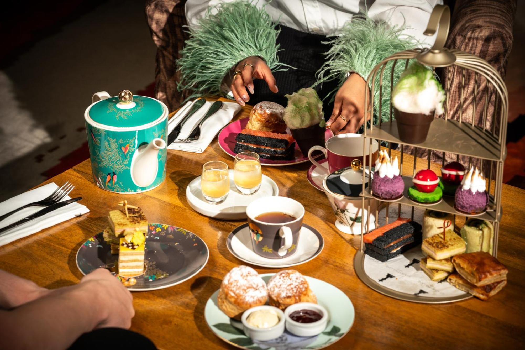 Hotel St Martins Lane Londýn Exteriér fotografie The photo features a beautifully arranged afternoon tea setting. In the center, there's an elegant tiered stand filled with various desserts, including colorful cupcakes and small pastries. Surrounding the stand are plates with additional treats, suc